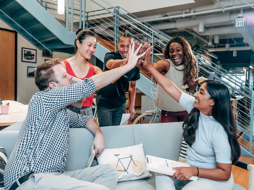 accountability partners and why they work - A multicultural office team high-fiving and celebrating a successful collaboration.