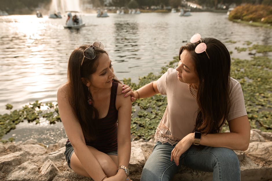 accountability partners and why they work - Two women having a heart-to-heart conversation by a sunny lakeside.