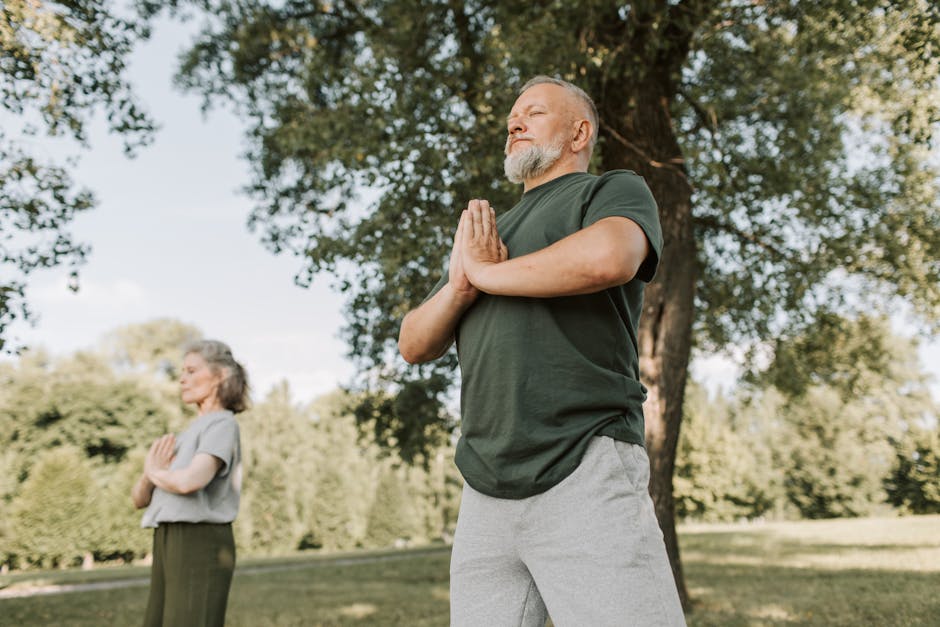 breathing exercises for stress and anxiety relief - Elderly couple meditating in a peaceful park setting, promoting a healthy lifestyle.