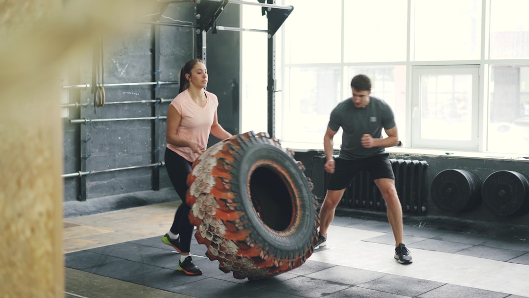 gamified wellness - Man and woman flipping tire in gym workout.