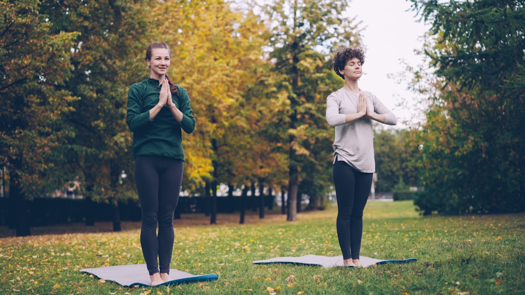 self-care routine - Two women practicing yoga outdoors in autumn park.