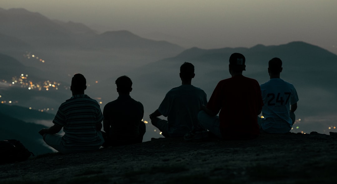 Five people sit on a hilltop overlooking a distant city.
