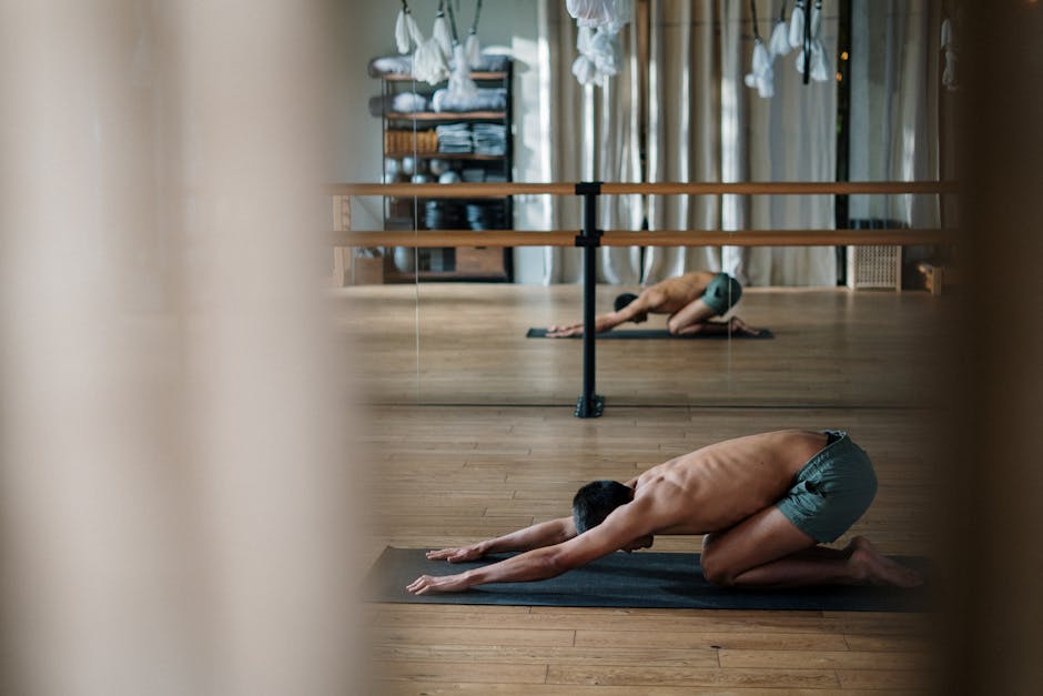 body scan meditation - Shirtless man doing yoga in a calm studio setting with mirrored reflections.