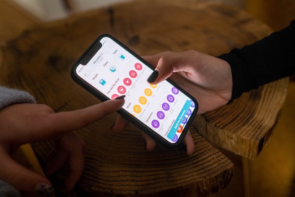 best meditation apps - Close-up of hands using a fertility tracking app on a smartphone indoors.