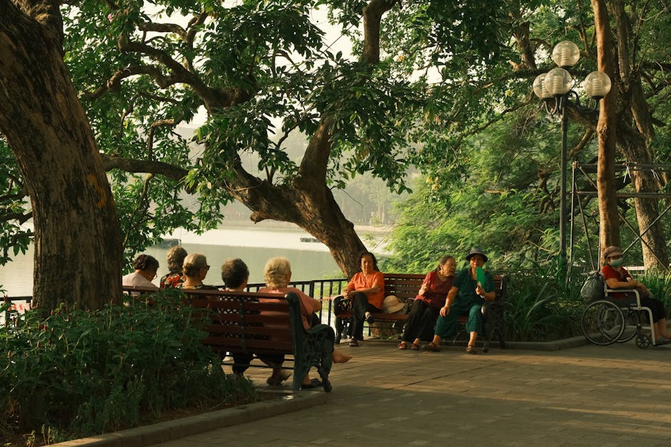 mindfulness for social anxiety - A serene scene of senior adults enjoying a chat in a lush park beside a tranquil lake.