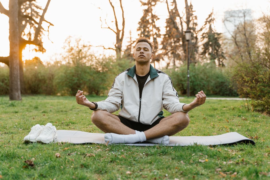 loving-kindness meditation - Man meditating outdoors in a tranquil park setting at sunset, promoting relaxation and mindfulness.
