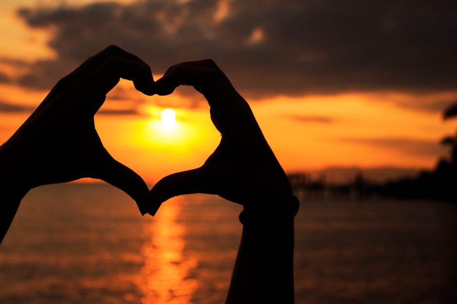 loving-kindness meditation - Silhouette of hands forming a heart against a beautiful seaside sunset.