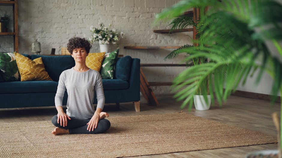 box breathing - Woman meditating in a cozy living room with natural decor, promoting relaxation.