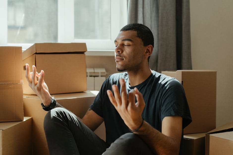 box breathing - A young man practices meditation surrounded by cardboard boxes during a move.