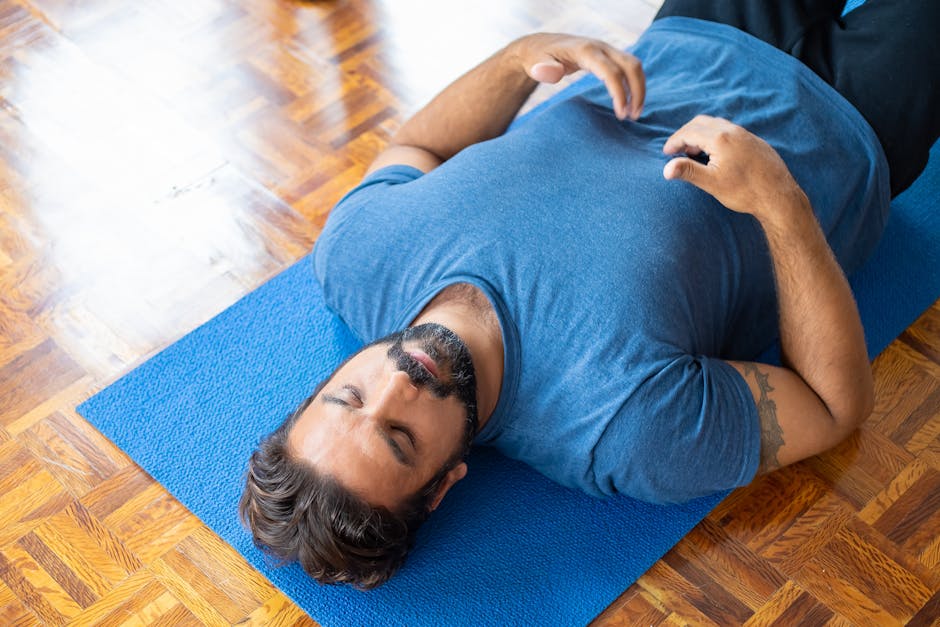 progressive muscle relaxation - Adult man lying on a blue yoga mat indoors with eyes closed, focusing on relaxation and mindfulness.