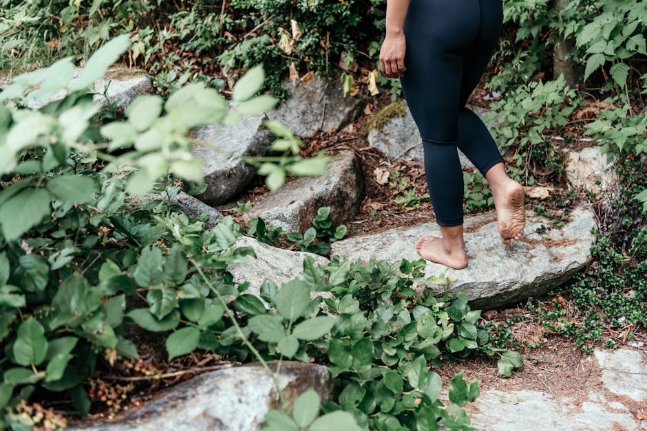 walking meditation - Adult walking barefoot on a rocky path surrounded by greenery, embracing nature's connection.