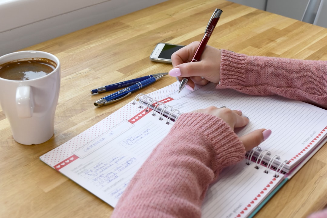 weekly mindfulness news - A person writing in a notebook with coffee.