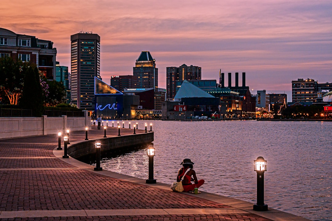 mindfulness and mental wellness - Person sitting by waterfront overlooking city skyline at dusk.