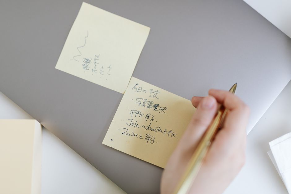 implementation intentions - Close-up of a hand writing notes on sticky notes placed on a laptop, emphasizing planning and organization.