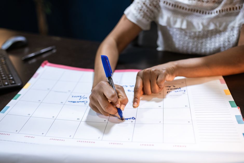 implementation intentions - A woman marks important dates on her desk calendar, planning upcoming events.