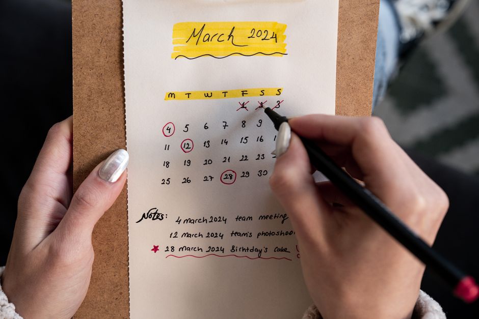 micro habits - Close-up of a woman's hands organizing a planner for March 2024 with handwritten notes and highlights.