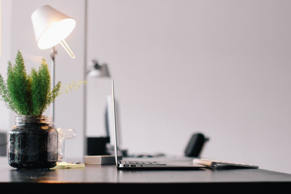 monotasking - Stylish modern office desk with laptop, lamp, and indoor plant for productive work environment.