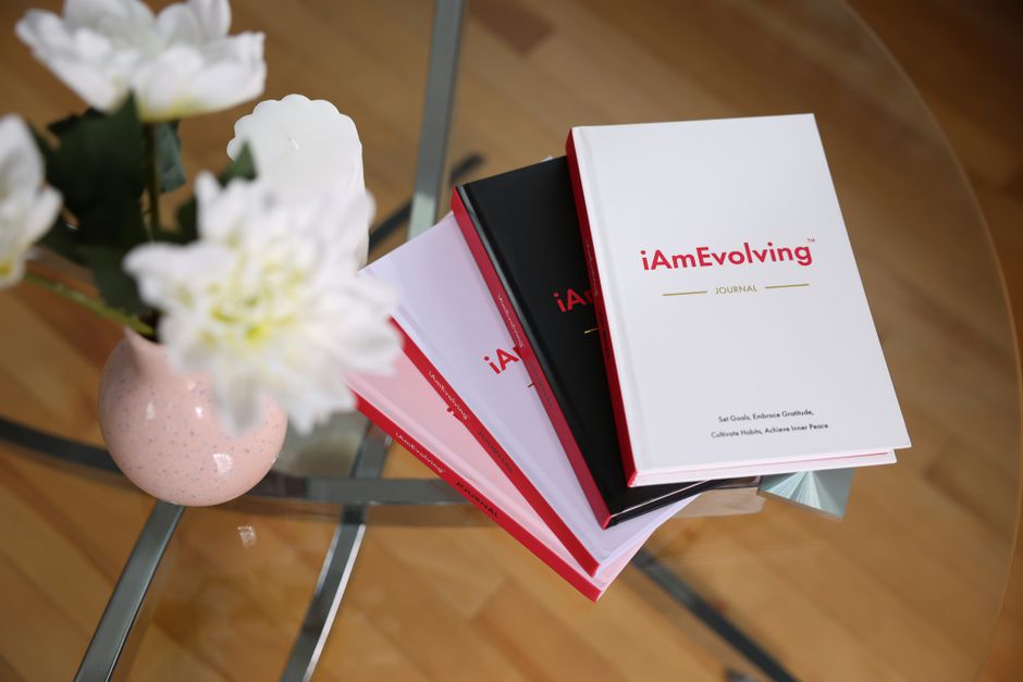 mental wellness - An elegant journaling scene featuring iAmEvolving books and white flowers on a glass table, ideal for self-care.