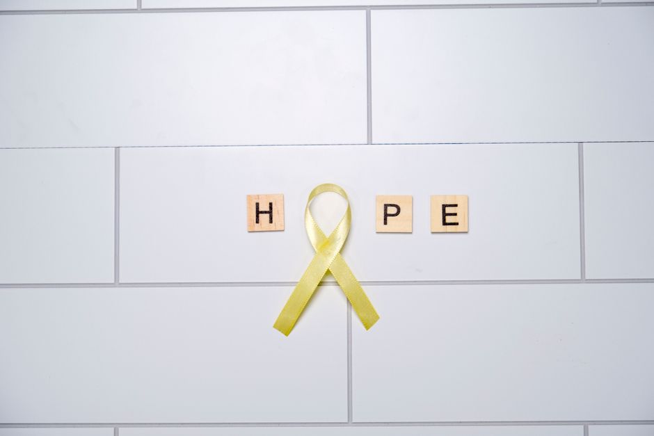 mental wellness - A yellow ribbon forming the word 'hope' with tiles on a white tiled background, symbolizing awareness and support.