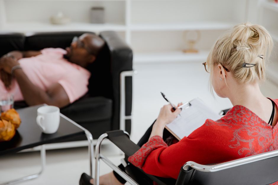 mental wellness news - A professional therapist takes notes during a therapy session, engaging with a client.