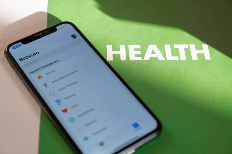 mental wellness news - Close-up of a smartphone displaying a health app on a green surface with 'HEALTH' text.
